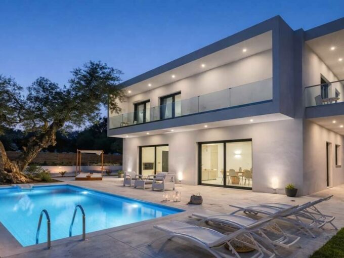 Exterior of Villa Agua in Bel Air, Estepona, with a two-storey modern house, glass balconies and a pool at dusk